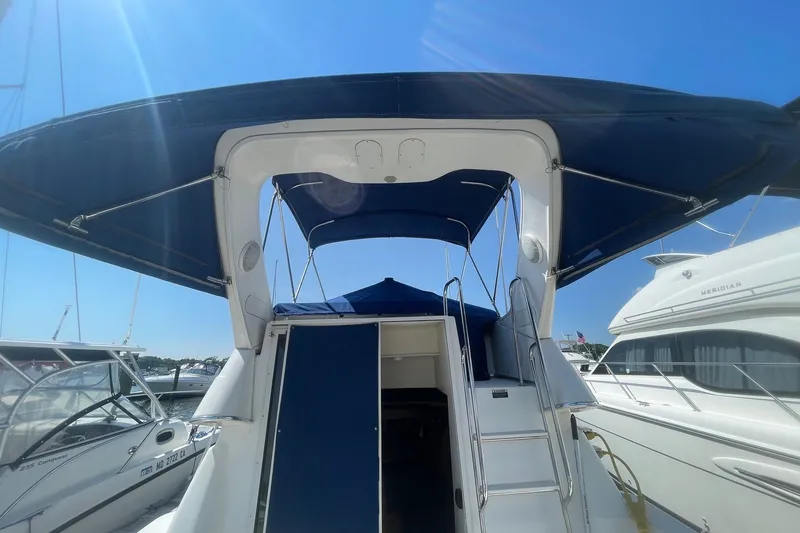 Slide: The Image of 2007 Bayliner Discovery 288 boat with blue canopy, docked under clear sky. - 24
