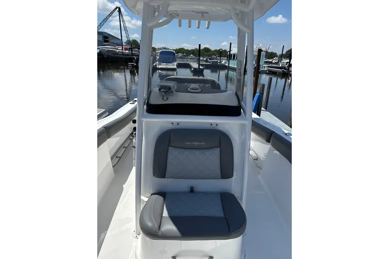 Slide: The Image of 2024 NauticStar 222L Offshore boat interior with gray seating, docked at marina. - 5