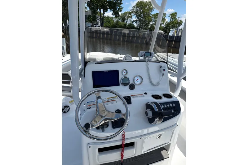Slide: The Image of 2024 NauticStar 222L Offshore boat dashboard with steering wheel and navigation instruments. - 2