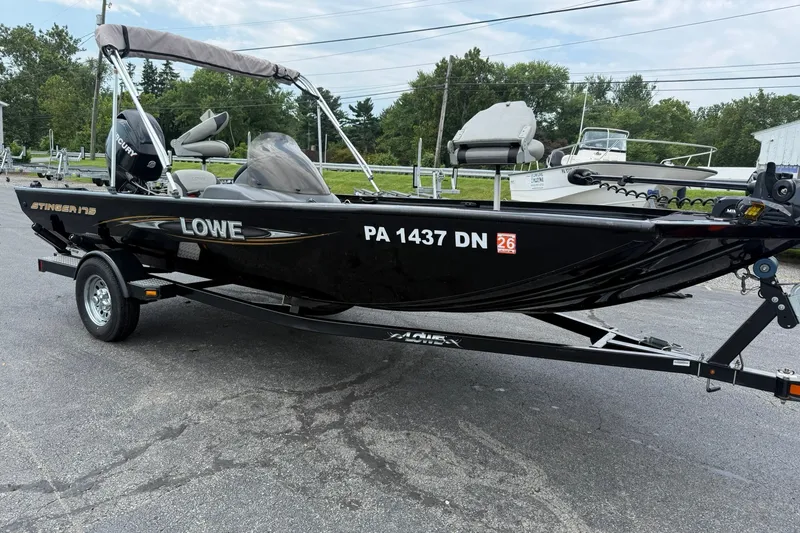 Slide: The Image of 2014 Lowe Stinger 175 boat on trailer, parked outdoors, showcasing sleek black design. - 7