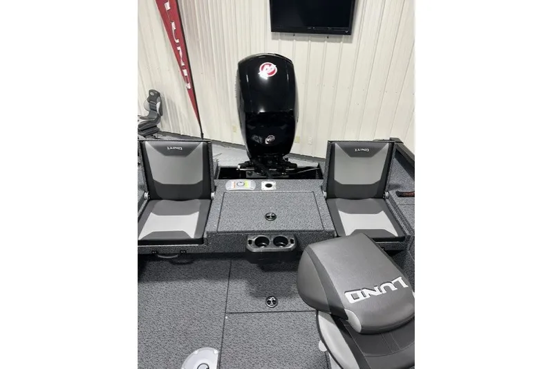 Slide: The Image of 2027 Lund 1875 Impact XS boat interior with seating and motor, in showroom setting. - 5