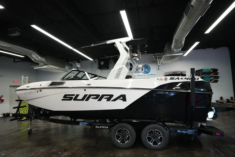 The Image of 2024 Supra SA 450 boat in showroom, sleek design, black and white color scheme. - 1