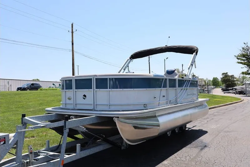 Slide: The Image of 2025 South Bay 220 RS LE 2.75 pontoon boat on trailer, parked outdoors. - 4