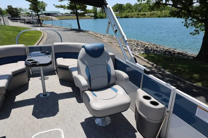 Slide: The Image of 2025 South Bay 220 RS LE 2.75 pontoon boat interior with plush seating by a lake. - 11