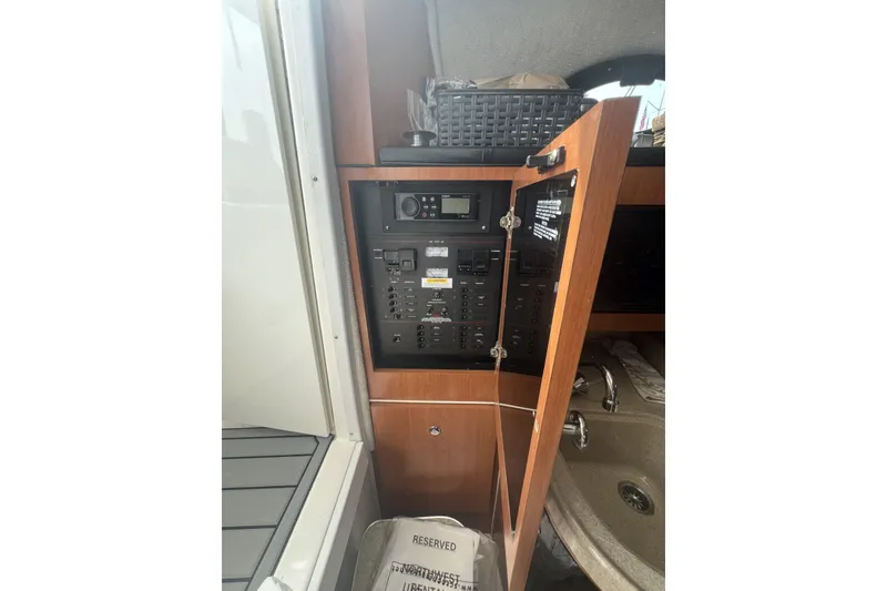 Slide: The Image of Electrical panel inside 2005 Wellcraft 290 Coastal boat, with open wooden cabinet door. - 12