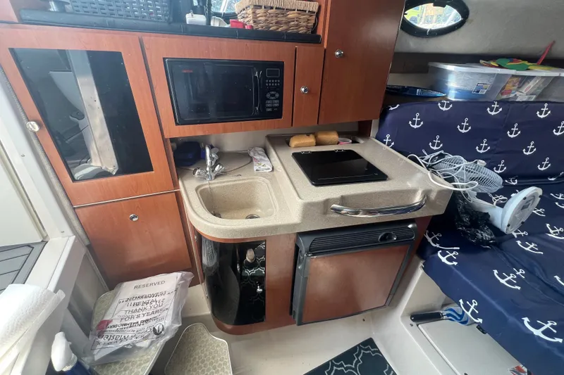 Slide: The Image of Compact kitchen area in a 2005 Wellcraft 290 Coastal boat, featuring a sink and microwave. - 11