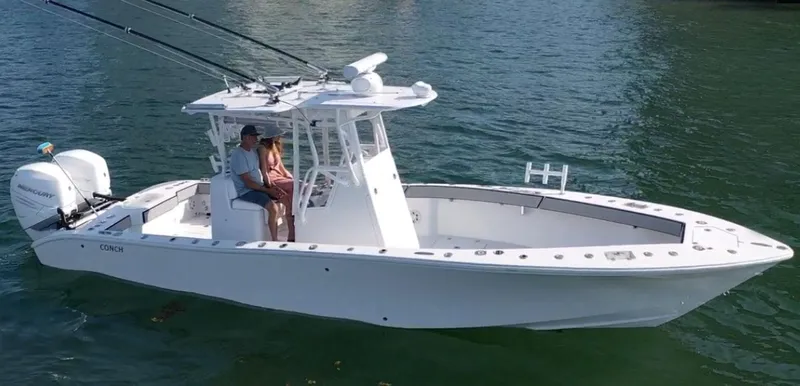 The Image of 2018 Conch 30 boat on water with two people seated, featuring dual outboard engines. - 1