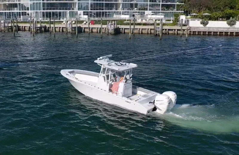 Slide: The Image of 2018 Conch 30 boat cruising on water near a modern waterfront building. - 18
