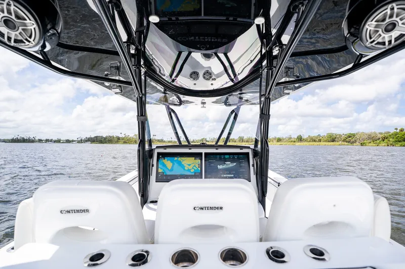 Slide: The Image of 2025 Contender 39 ST boat interior with advanced navigation screens on a calm waterway. - 30