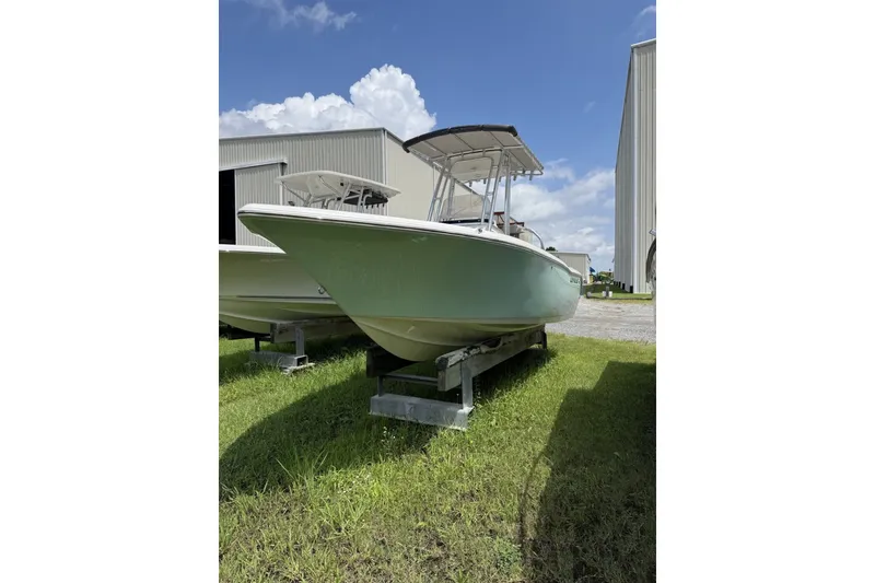 The Image of 2027 Key West 203 FS boat on grass near industrial buildings under blue sky. - 1