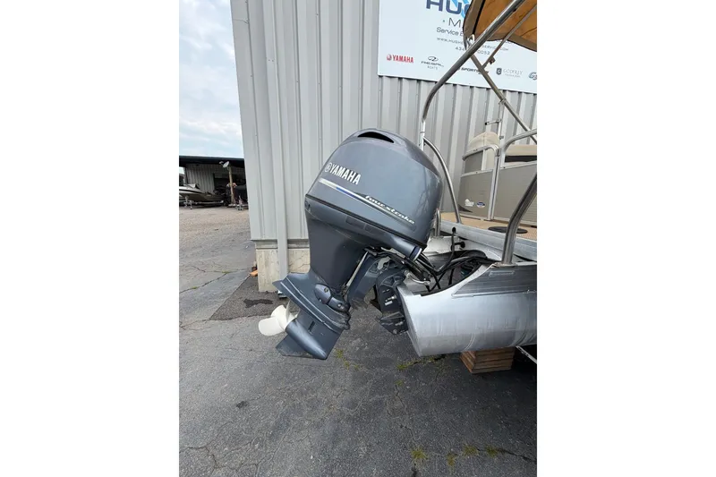 Slide: The Image of 2014 Godfrey SWEETWATER 2086 with Yamaha outboard motor, parked near a metal building. - 7