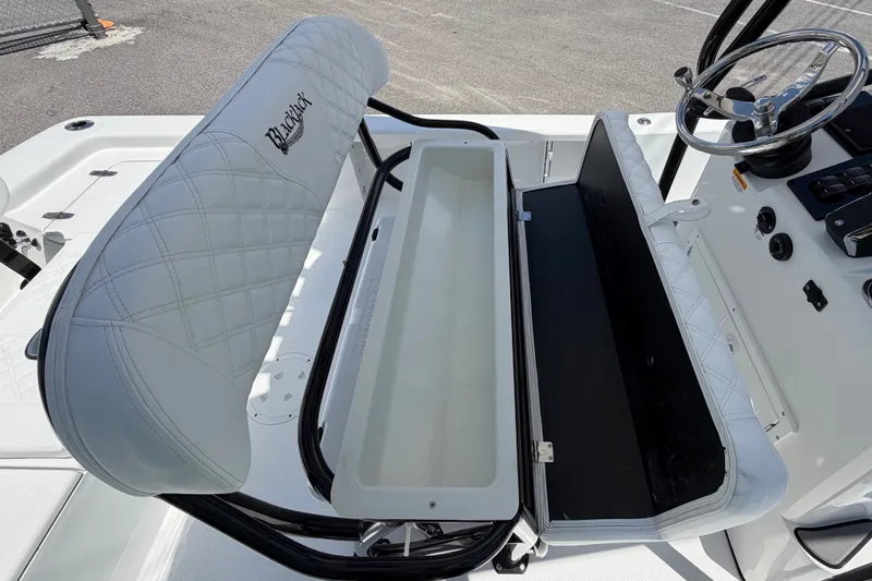 Slide: The Image of The image shows the helm of a BlackJack 224 boat with a cushioned seat and storage space. - 13