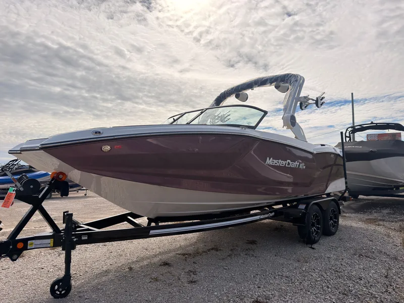 Slide: The Image of A 2027 MasterCraft NXT22 boat on a trailer under a cloudy sky. - 4