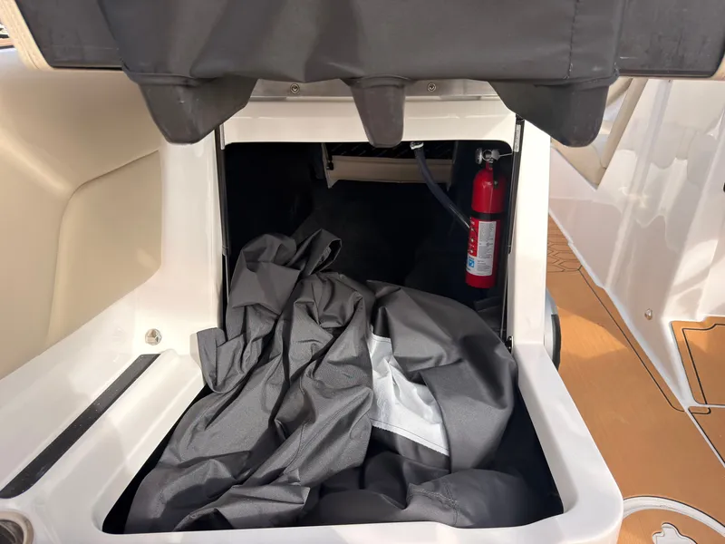 Slide: The Image of A storage compartment on a MasterCraft NXT22 boat with a cover and a fire extinguisher. - 38