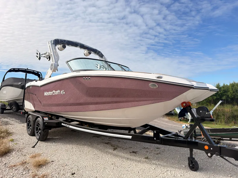 Slide: The Image of A 2027 MasterCraft NXT22 boat on a trailer under a cloudy sky. - 3
