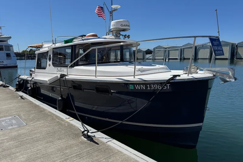 Slide: The Image of 2018 Ranger Tugs R-27 boat docked, displaying "For Sale" sign, with American flag. - 1