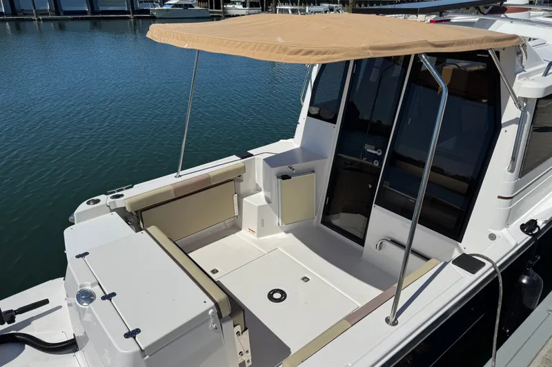 Slide: The Image of 2018 Ranger Tugs R-27 boat with beige canopy, docked on calm water. - 10