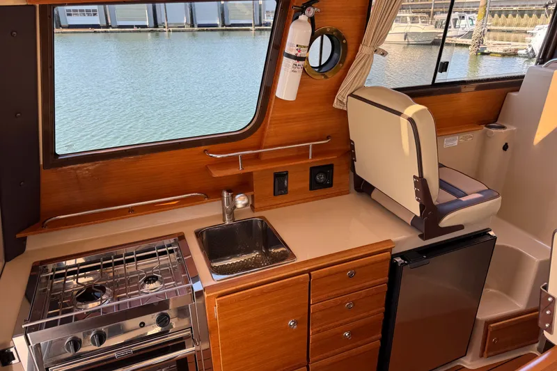 Slide: The Image of Interior of 2018 Ranger Tugs R-27 boat with kitchen and seating area. - 14