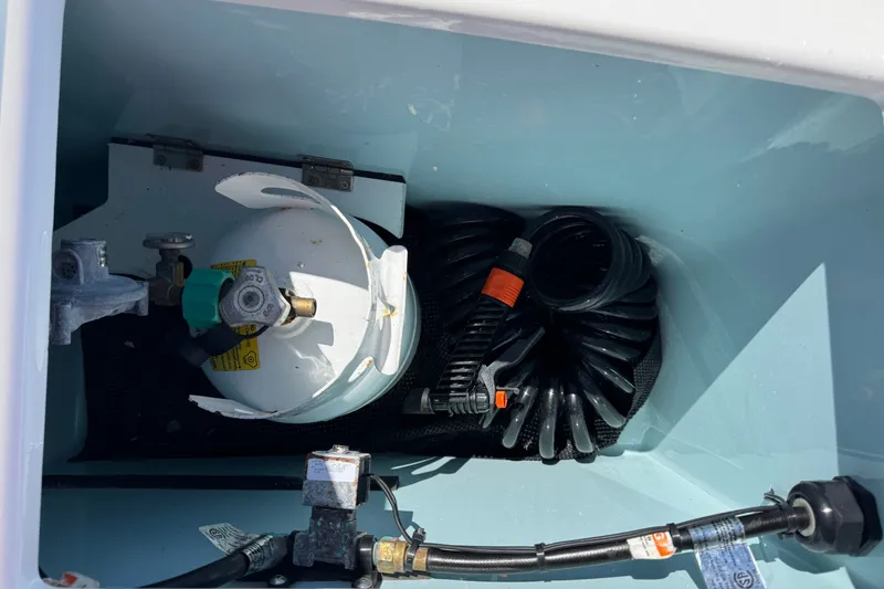 Slide: The Image of 2018 Ranger Tugs R-27 storage compartment with propane tank and coiled hose. - 7