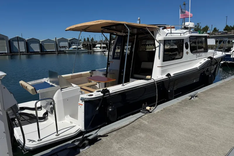 Slide: The Image of 2018 Ranger Tugs R-27 docked at marina, featuring spacious deck and canopy. - 2