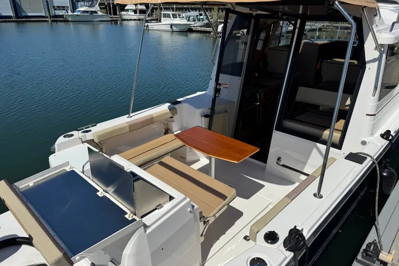 Slide: The Image of 2018 Ranger Tugs R-27 boat with outdoor seating and table, docked at a marina. - 4