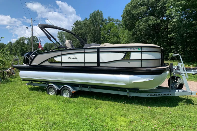 Slide: The Image of 2022 Barletta Lusso 23UC pontoon boat on trailer, parked on grassy area. - 4