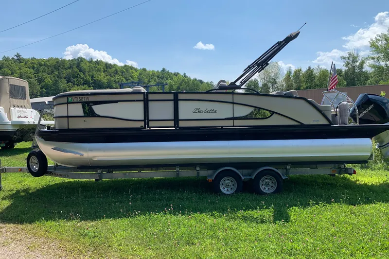 Slide: The Image of 2022 Barletta Lusso 23UC pontoon boat on trailer, parked on grass. - 2
