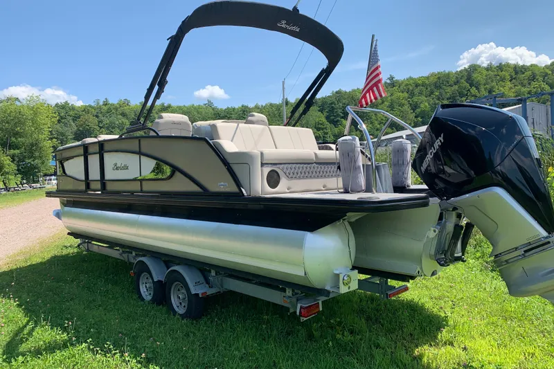 Slide: The Image of 2022 Barletta Lusso 23UC pontoon boat on trailer, parked on grass with American flag. - 3