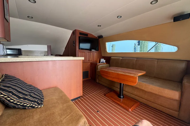 Slide: The Image of Interior of a 2004 Luhrs 38 Convertible with cozy seating and a wooden table. - 19