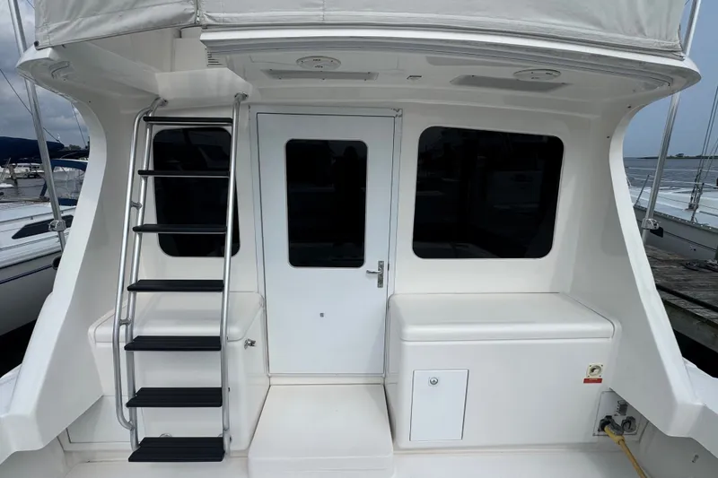 Slide: The Image of 2004 Luhrs 38 Convertible yacht with ladder and cabin door, docked at marina. - 13