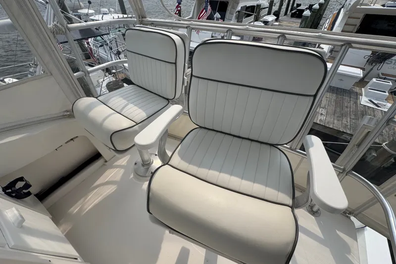 Slide: The Image of 2004 Luhrs 38 Convertible boat interior with white cushioned seats and marina view. - 34