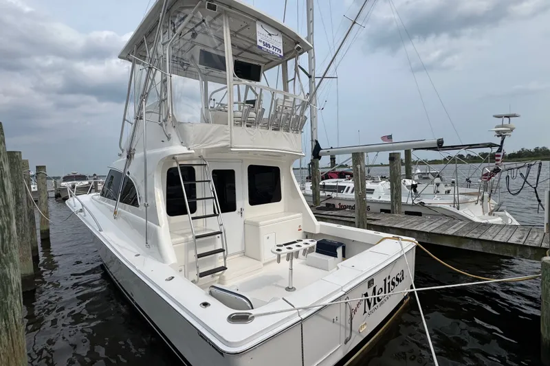 Slide: The Image of 2004 Luhrs 38 Convertible yacht docked at marina, featuring spacious deck and flybridge. - 42