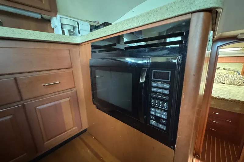 Slide: The Image of 2004 Luhrs 38 Convertible yacht kitchen with built-in microwave and wooden cabinetry. - 32