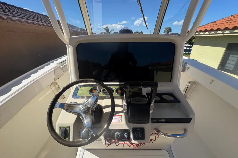 Slide: The Image of 2008 Scout 282 Sportfish helm with steering wheel and controls under clear blue sky. - 57