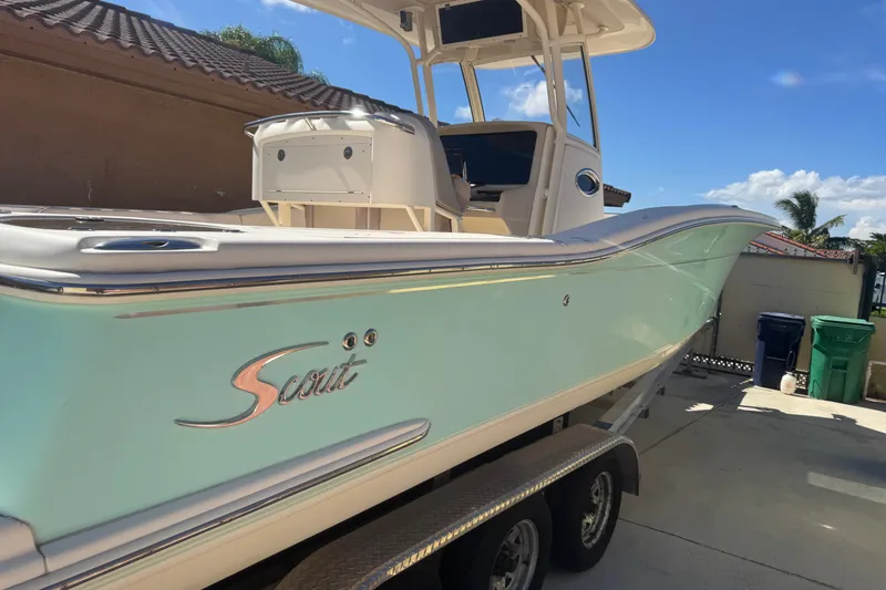 Slide: The Image of 2008 Scout 282 Sportfish boat on trailer, parked outdoors under clear blue sky. - 1