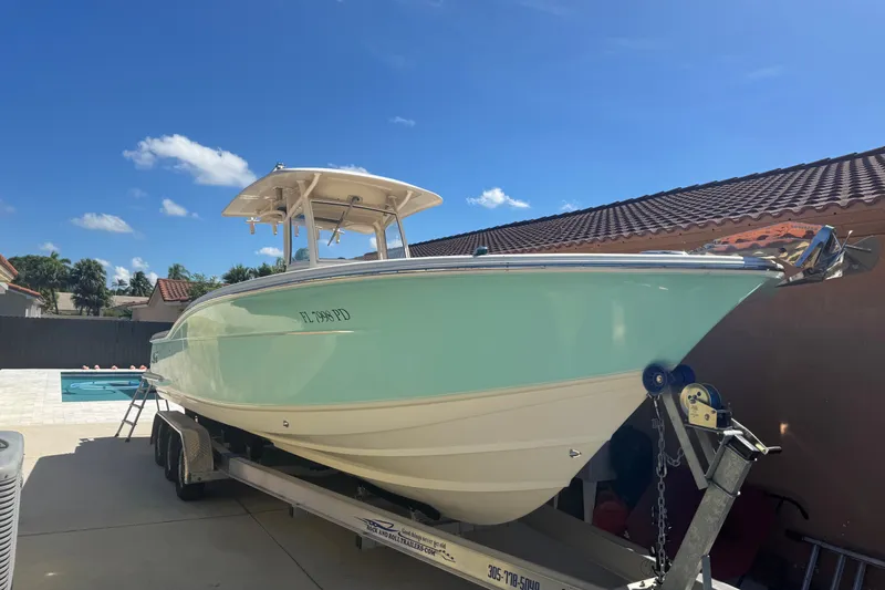 The Image of 2008 Scout 282 Sportfish boat on trailer, parked in sunny residential driveway. - 0