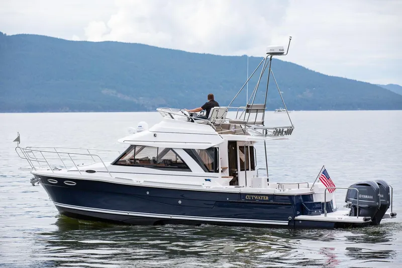 The Image of 2027 Cutwater C-32 CB boat cruising on a serene lake with mountainous backdrop. - 0
