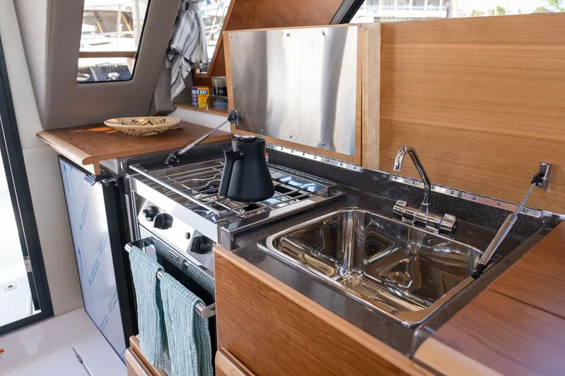 Slide: The Image of Compact kitchen in 2027 Cutwater C-32 CB boat with stove, sink, and wooden cabinetry. - 24