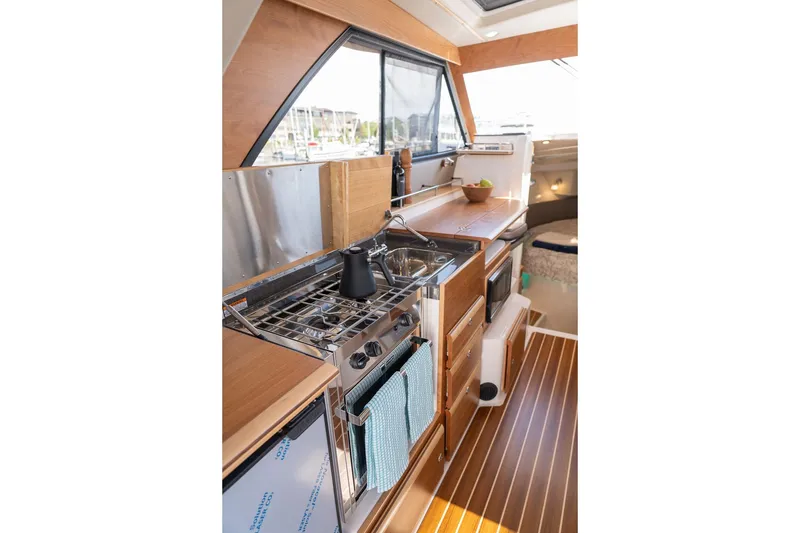 Slide: The Image of Interior of 2027 Cutwater C-32 CB boat featuring a compact kitchen area. - 21