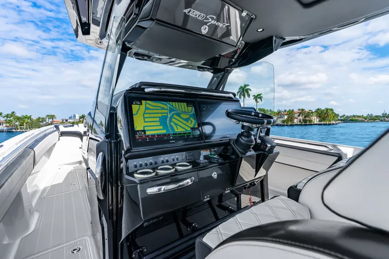 Slide: The Image of 2024 Nor-Tech 450 Sport boat cockpit with advanced navigation system, sleek design, and waterfront view. - 64