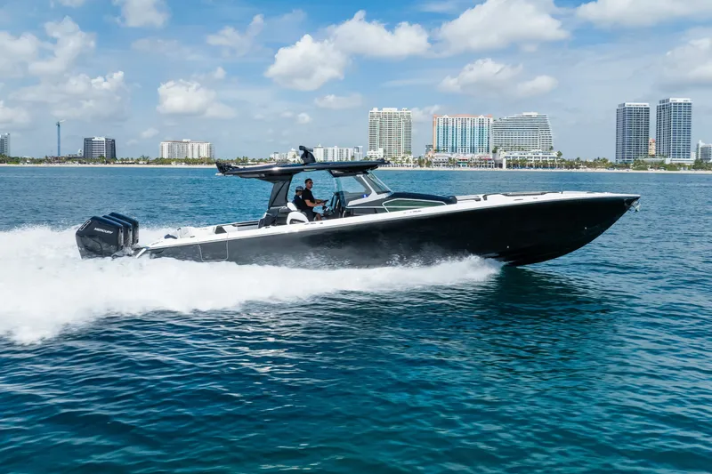 Slide: The Image of 2024 Nor-Tech 450 Sport boat cruising on blue ocean near city skyline. - 13