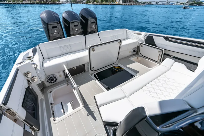 Slide: The Image of 2024 Nor-Tech 450 Sport boat interior with open storage compartments and triple Mercury engines. - 61
