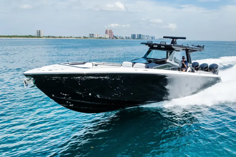 Slide: The Image of 2024 Nor-Tech 450 Sport boat cruising on clear blue water near a city skyline. - 21