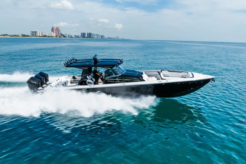 Slide: The Image of 2024 Nor-Tech 450 Sport boat cruising on open water, city skyline in background. - 19