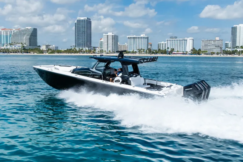 Slide: The Image of 2024 Nor-Tech 450 Sport boat cruising on blue ocean near city skyline. - 23