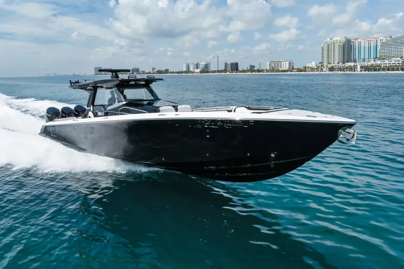 Slide: The Image of 2024 Nor-Tech 450 Sport boat cruising on clear blue ocean near city skyline. - 15