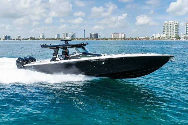 Slide: The Image of 2024 Nor-Tech 450 Sport boat cruising on clear blue water near a city skyline. - 14
