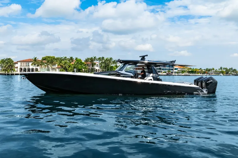 Slide: The Image of 2024 Nor-Tech 450 Sport boat cruising on a sunny day near waterfront homes. - 5