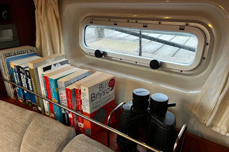 Slide: The Image of Books and binoculars on a shelf inside a 1999 Oyster 53 Deck Saloon yacht. - 39