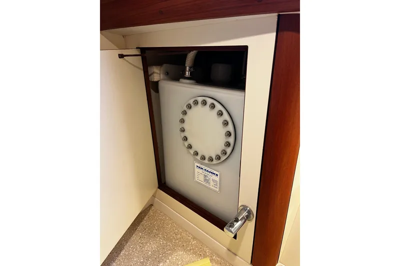Slide: The Image of Water tank compartment in 1999 Oyster 53 Deck Saloon yacht, featuring secure fittings and wooden trim. - 61